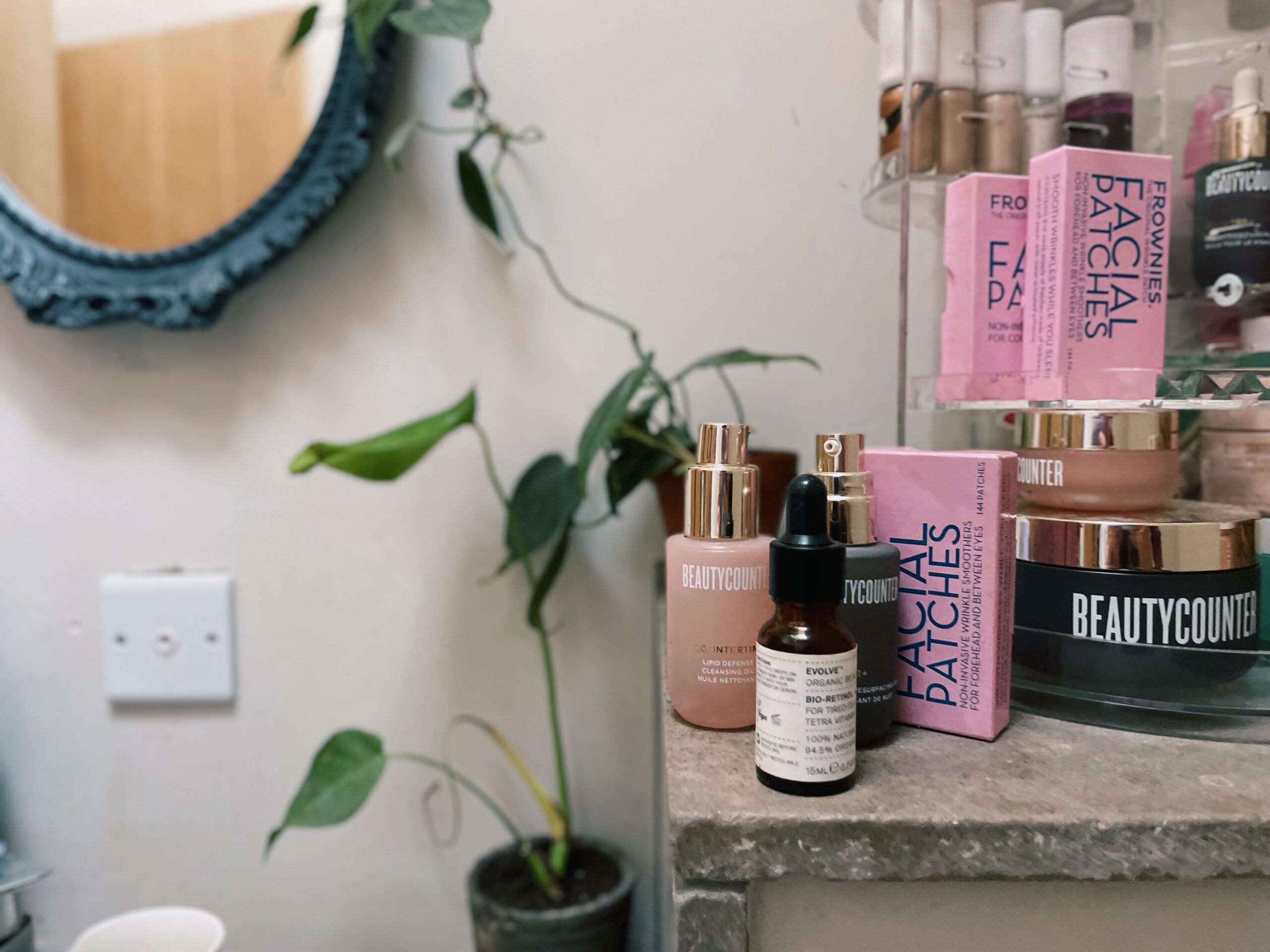 Lots of skincare bottles on a grey shelf with a plant to the left