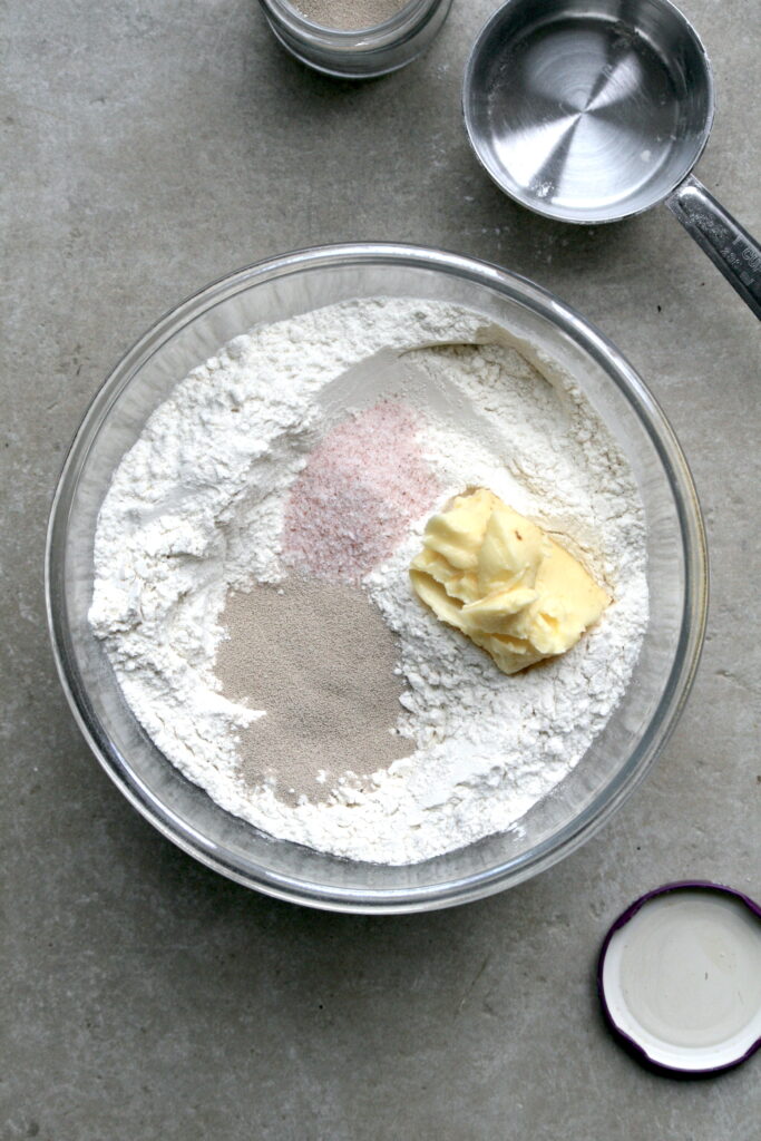 flour, yeast, butter and salt in a glass bowl on a grey flour
