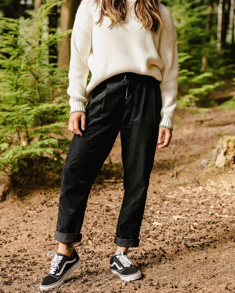 woman in a wood wearing black joggers and white jumper