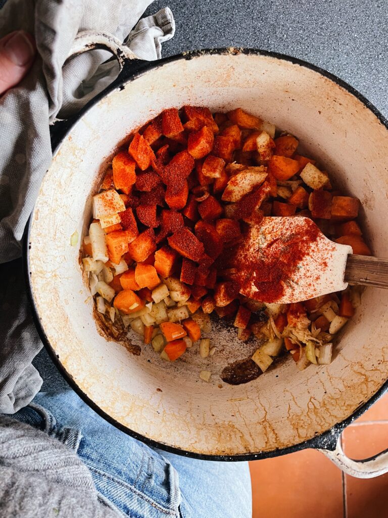 carrots and onions diced with red spice powder in a white casserole pot.